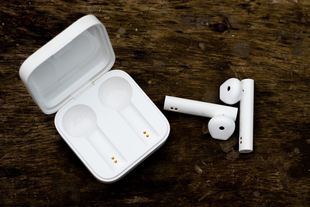 Wireless Bluetooth headphones and charging case for music on wooden background.